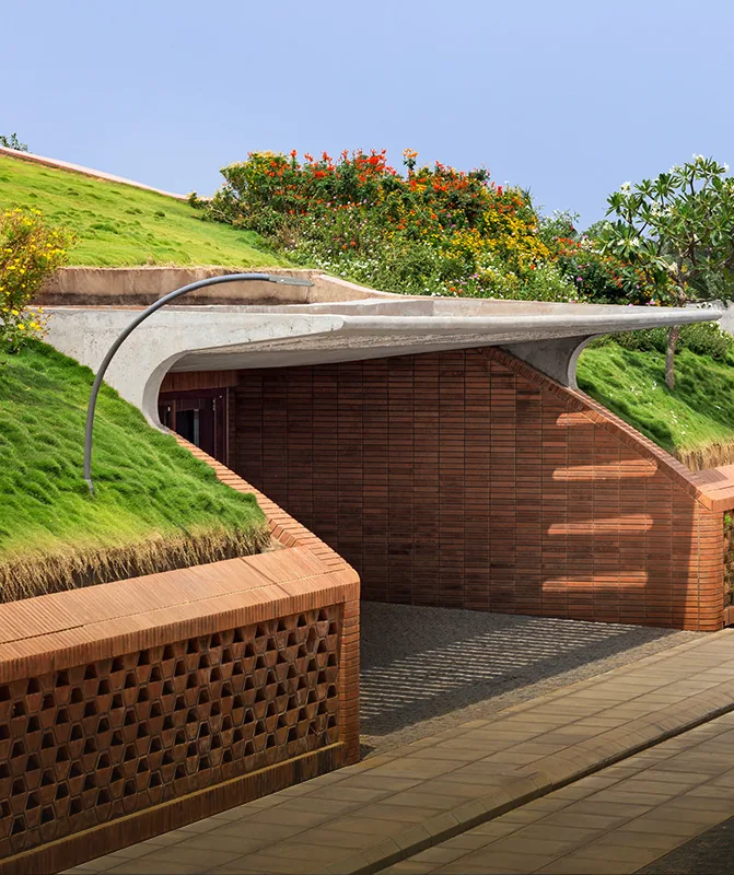 Total Environment After the Rain Earth-sheltered villa entrance under a curved green roof at After the Rain